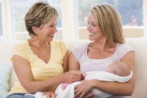 Grandmother and mother in living room with baby smiling